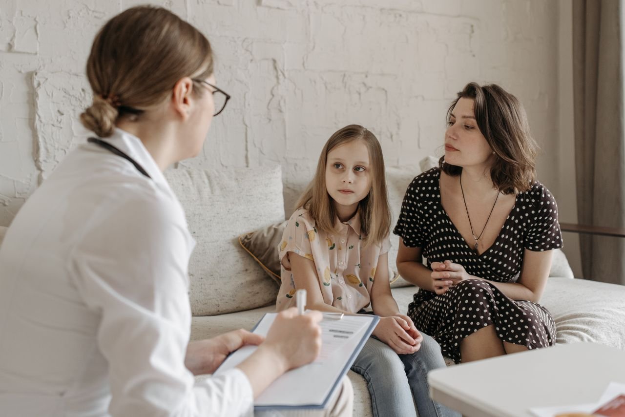 Home A mother and daughter consult with a doctor during a medical appointment indoors.